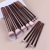 Professional makeup brush set with rose gold handles on beige surface