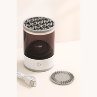 Electric makeup brush cleaner with USB charging cable and detachable silicone cleaning pad, designed for deep brush washing and drying.